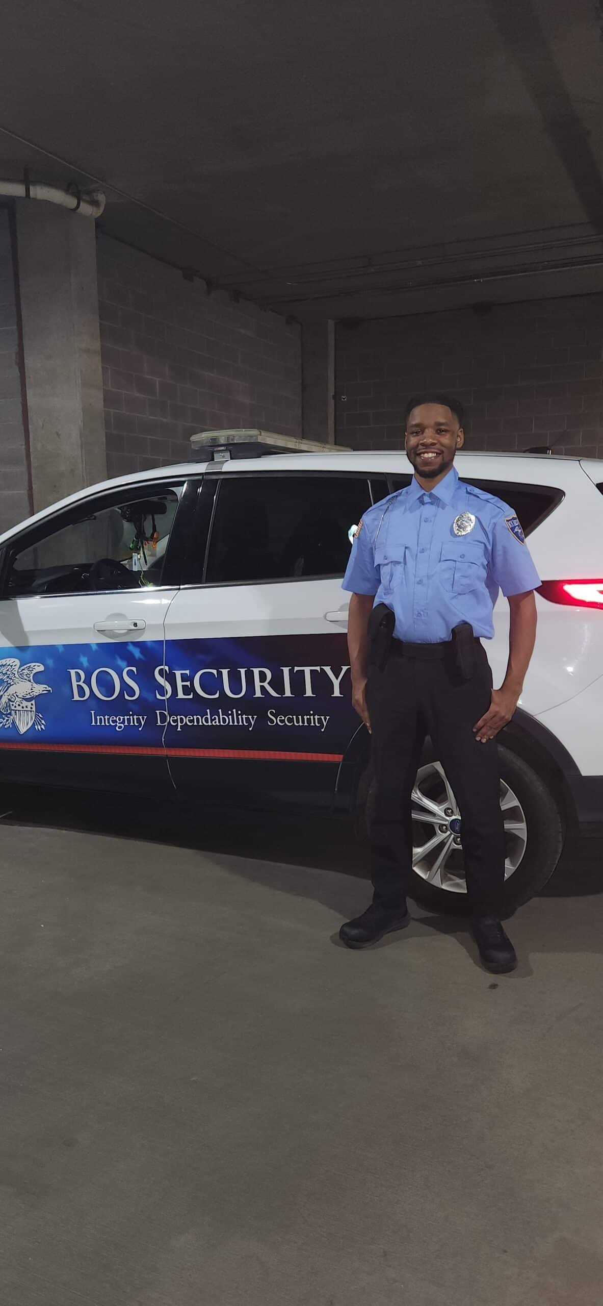Officer Antorian Lattimore stands in front of a BOS Security patrol vehicle.