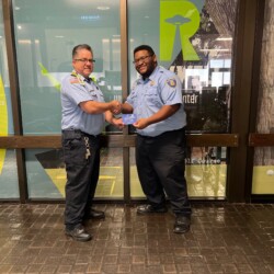 Two Transportation Security Officers are shaking hands and smiling in their uniforms.