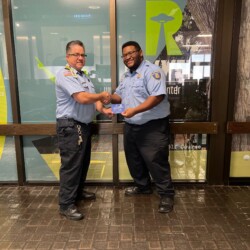 Program Manager Justin Dunbarr presenting TSO Torian McKnight with a 3 years service pin and appreciation note during National Security Officer Appreciation Week. Two Transportation Security Officers are shaking hands and smiling in their uniforms.