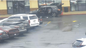 In front of the Planet Fitness there is a black SUV with its doors and trunk open and trash scattered around it.