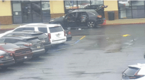 The suspect's vehicle is parked in the fire line outside of the Planet Fitness with its doors and trunk open and trash scattered around it. In front of the Planet Fitness there is a black SUV with its doors and trunk open and trash scattered around it.