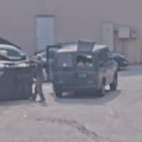A man begins taking personal trash out of the van and placing it into the private dumpster. A man begins taking personal trash out of the van and placing it into the private dumpster.