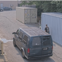 The van drives behind the commercial property to approach the private dumpster.
