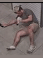 The injured male is laying on the floor of the elevator, holding his phone in his right hand and his right shoe in his left hand.