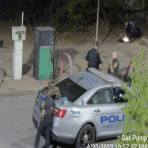 The suspects' belongings are placed on the trunk of the police vehicle while an officer continues to search them. Behind the police vehicle, two officers are standing with the female suspect and another officer continues to search more of the their belongings in the background. The suspects' belongings are placed on the trunk of the police vehicle while an officer continues to search them. Behind the police vehicle, two officers are standing with the female suspect and another officer continues to search more of the their belongings in the background.