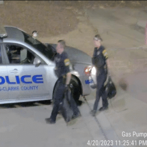 Two police officers carry the suspects' belongings off of the property. Two police officers carry the suspects' belongings off of the property.